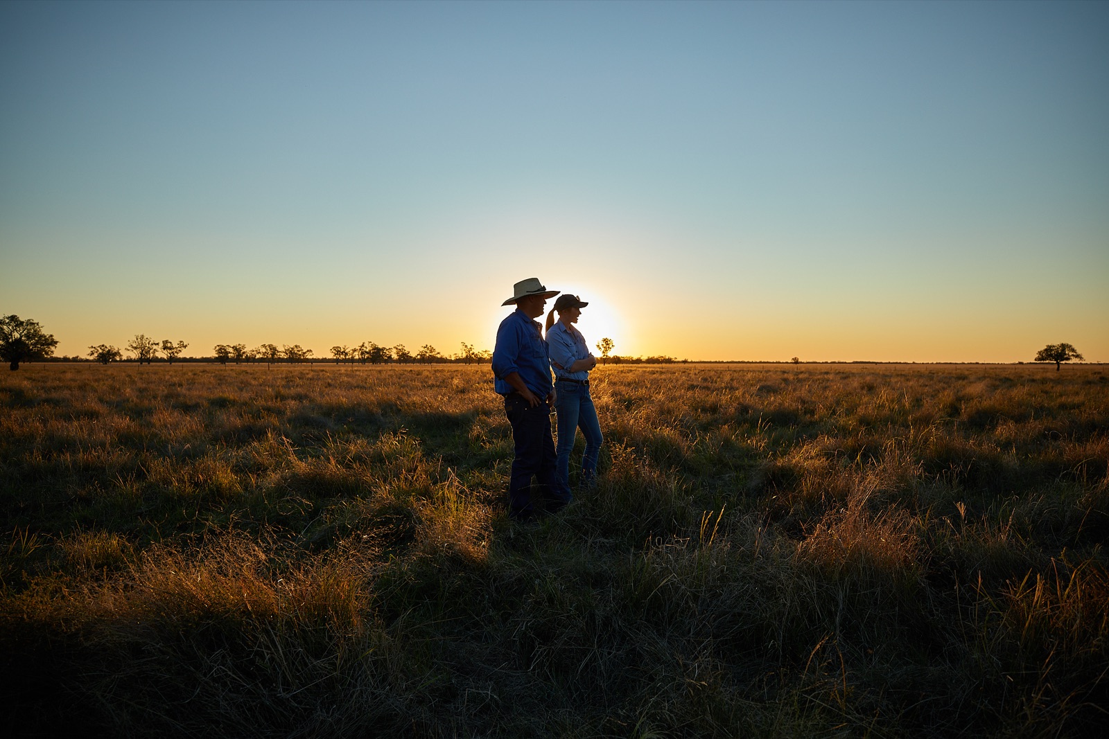 Two sheep producers standing in open pasture at sunset, central west New South Wales